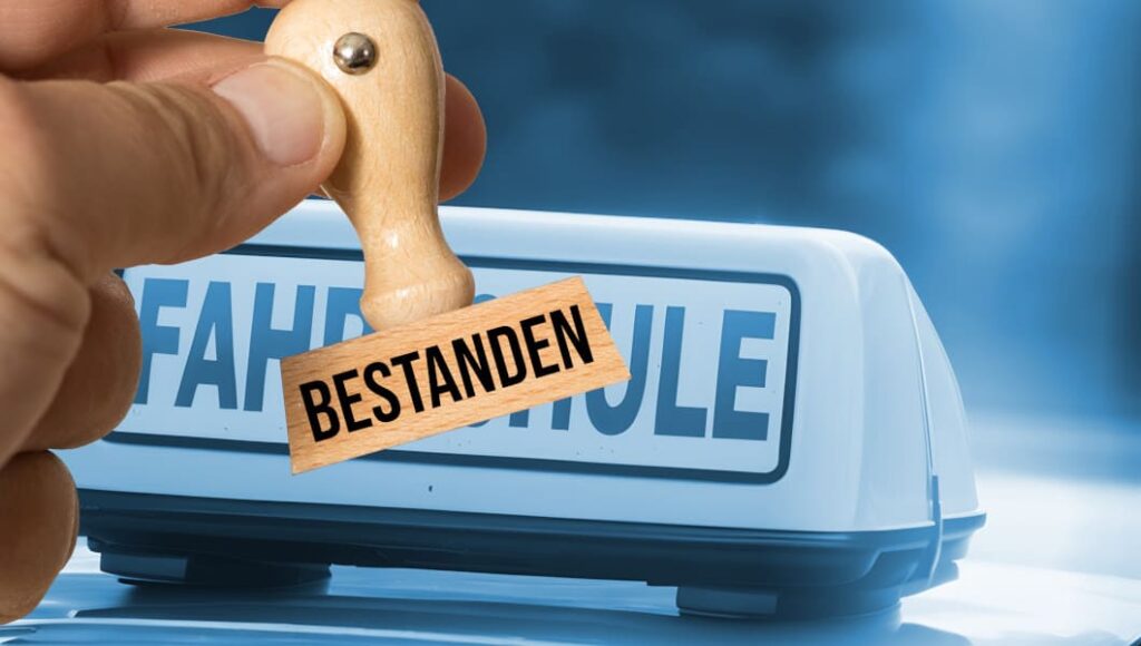 Praktische Fahrprüfung bestanden – Stempel vor einem Fahrschule-Schild
