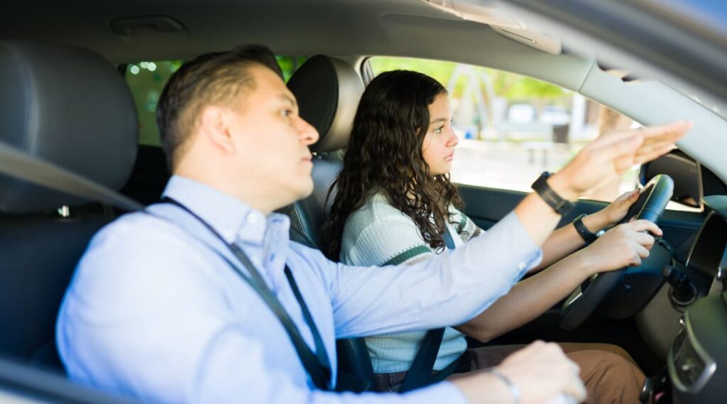 Praktische Fahrprüfung – Fahrprüfer gibt Anweisungen an Fahrschülerin während der Fahrt